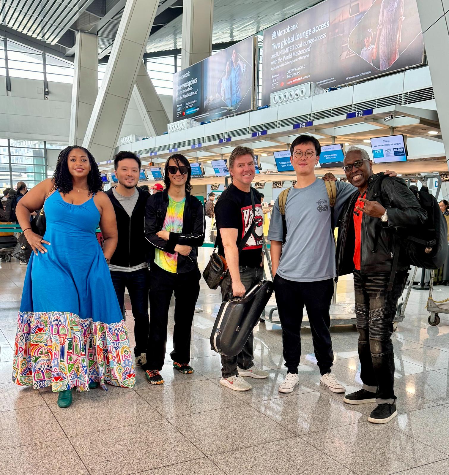Home 18 OnPoint band members with luggage and a saxophone case at Manila airport check-in